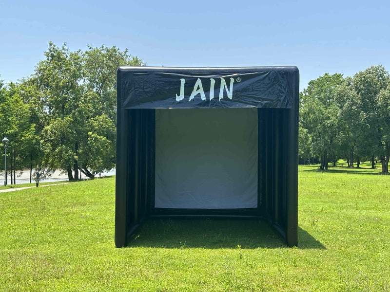 A well-maintained inflatable golf simulator tent set up on a manicured lawn, showcasing a clean impact screen and proper tension.