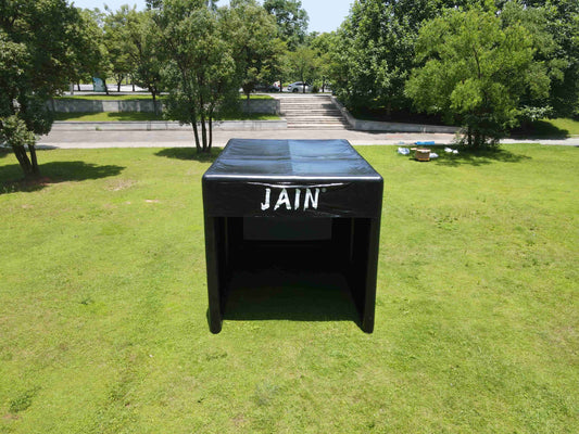 Front view of a JAIN outdoor inflatable golf simulator enclosure set up on a grassy lawn for backyard practice.