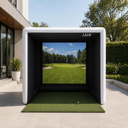 JAIN inflatable golf simulator tent set up in a modern backyard patio with a golf screen and hitting mat